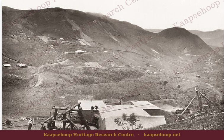 A De Kaap goldfield mine with corrugated-iron stamp mill and headgear on a hillside scarred by workings